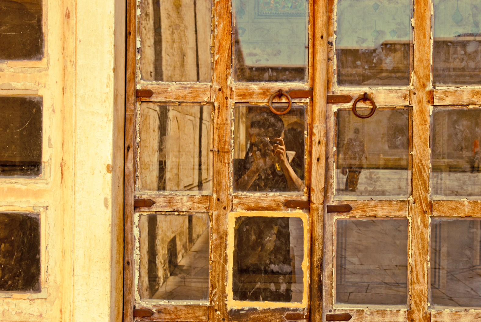 A camera-holding figure reflected in divided windowpanes
