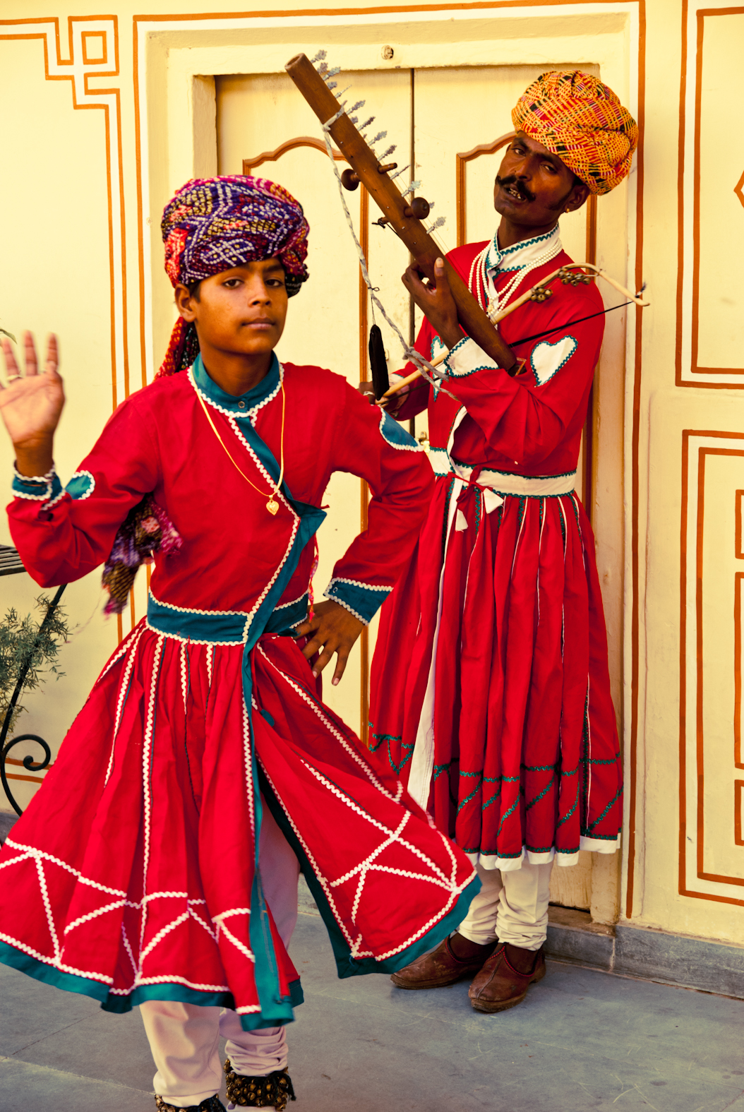 Two figures in red with a stringed instrument
