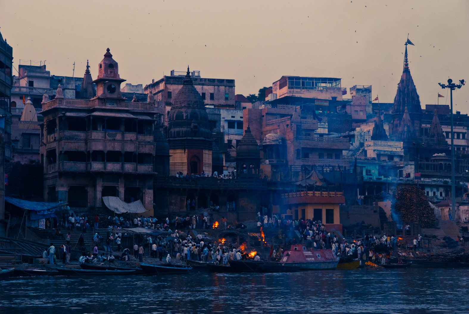 Waterfront buildings, people and points of firelight