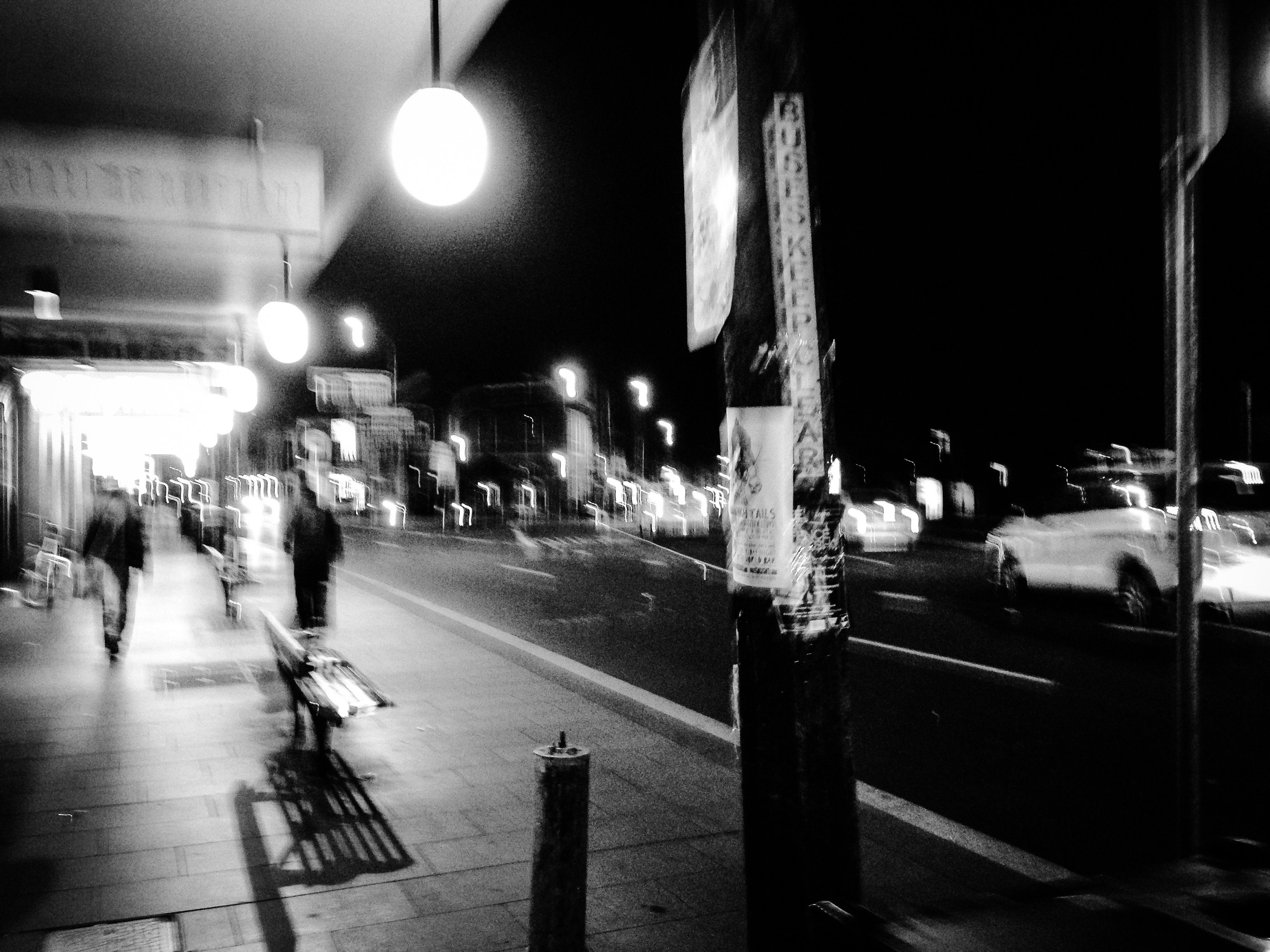 A black-and-white night street with blurred lights