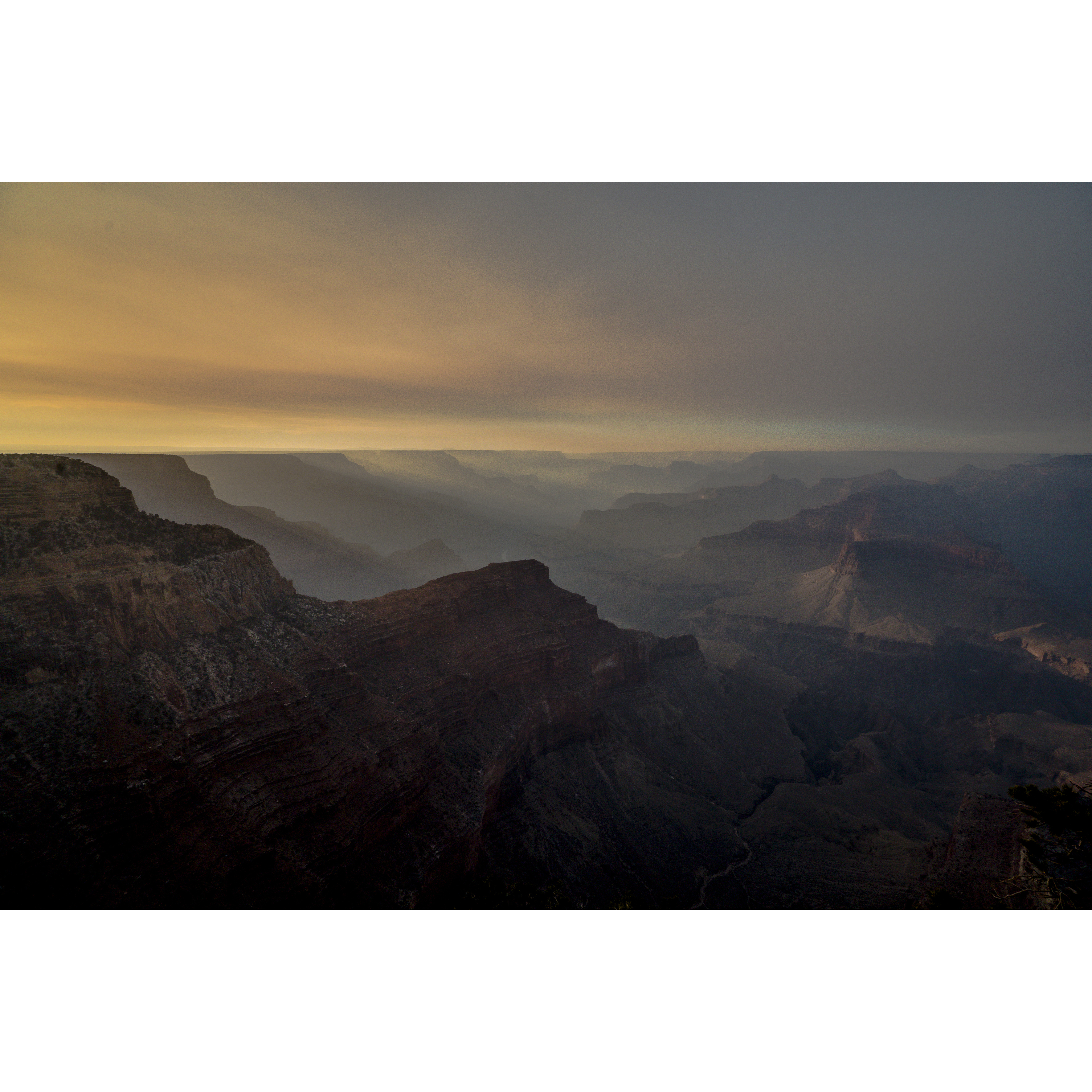 A canyon receding into haze and evening light, within the original white border